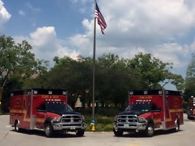 Two Ambulances Parked by a Flagpole